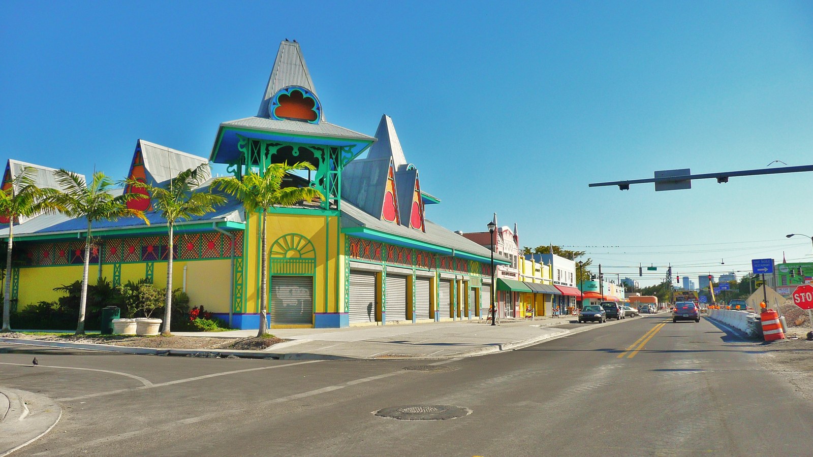 A brightly painted yellow, green, and red commercial building with Caribbean-style peaked roofs along a Little Haiti street
