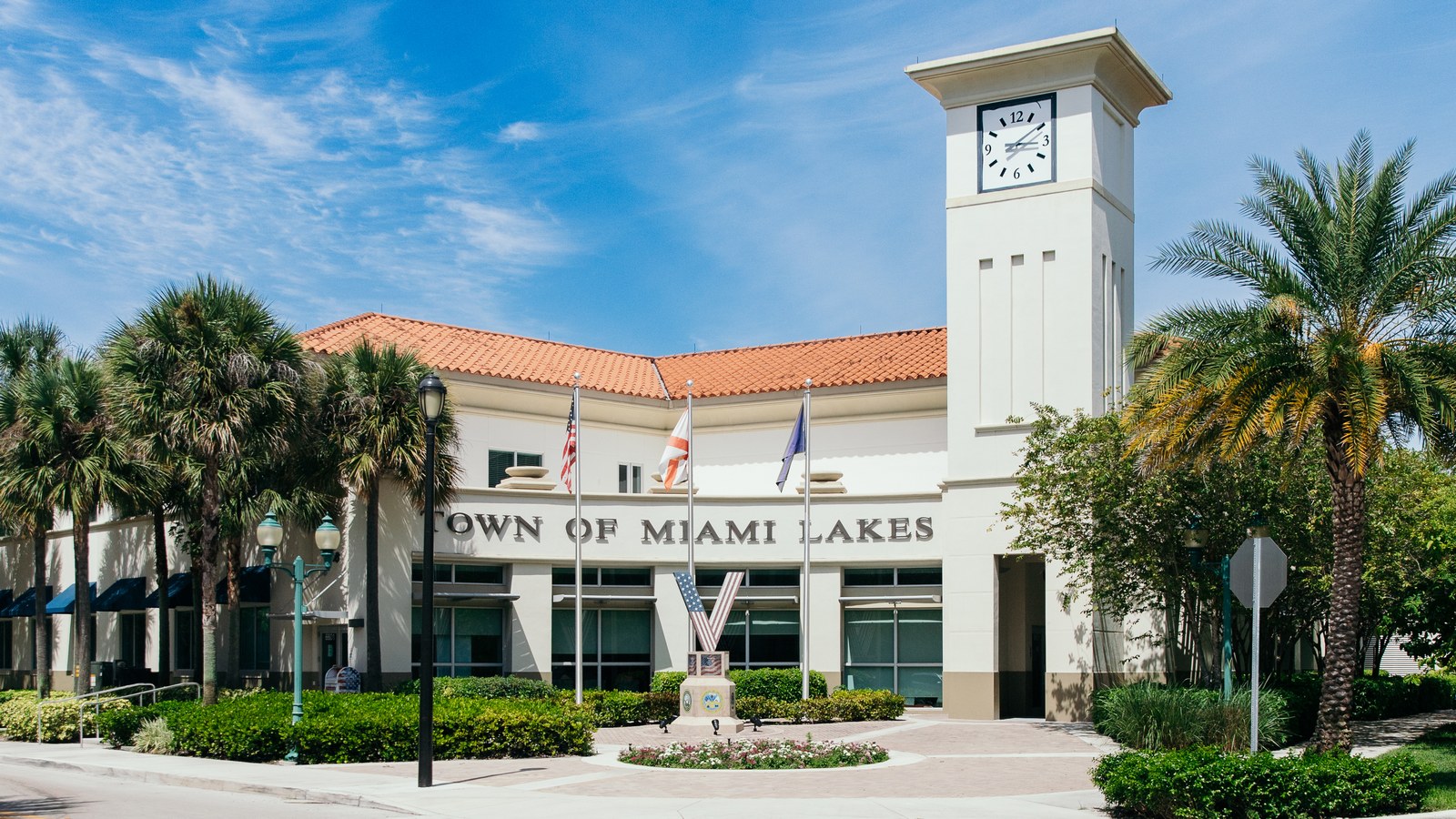 The Town Hall of Miami Lakes, a Mediterranean-style civic building with a clock tower, palm trees, and a 