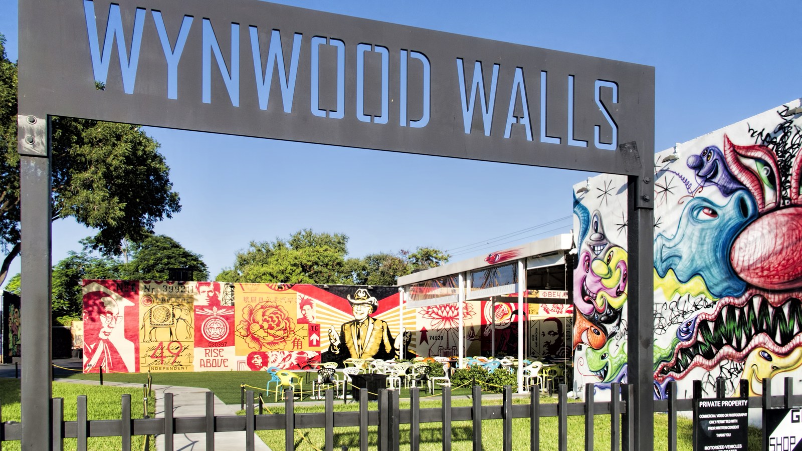 The Wynwood Walls entrance sign against a blue sky, with colorful murals covering the buildings behind it