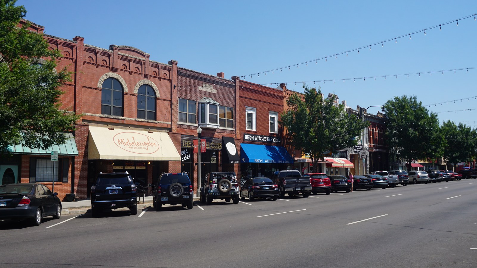 Storefronts including Bison Witches Bar & Deli along E Main Street in downtown Norman, Oklahoma