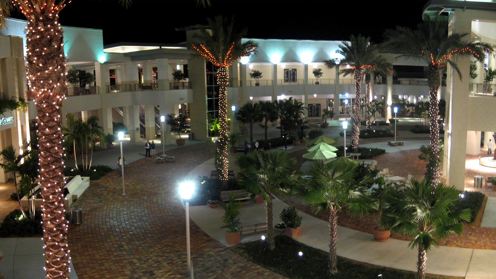 The palm-lined main court at Downtown at the Gardens, Palm Beach Gardens' open-air shopping and dining district, lit up in the evening