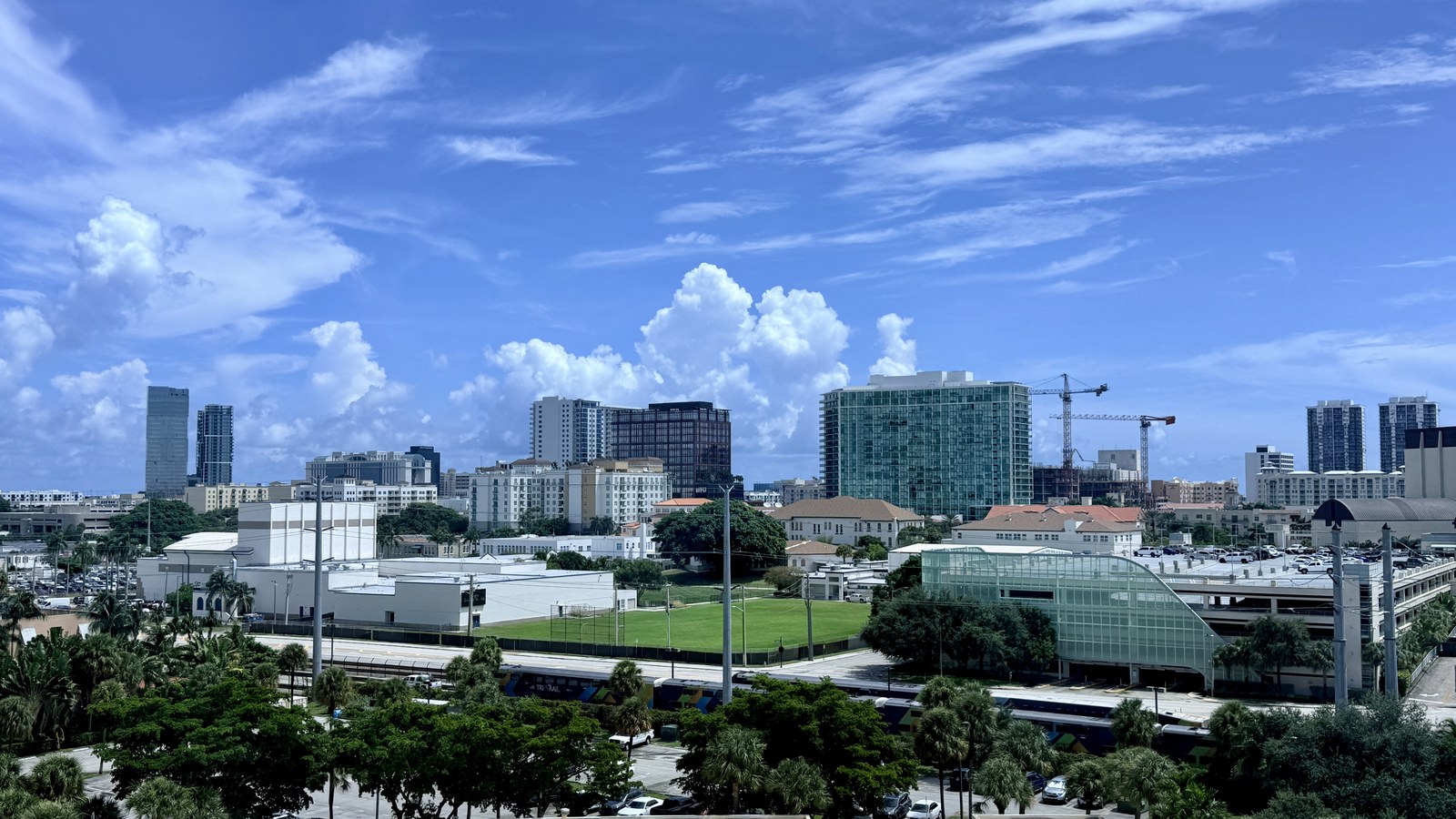 Downtown West Palm Beach's skyline on a summer afternoon, seen from across the Tri-Rail corridor with a train passing in the foreground