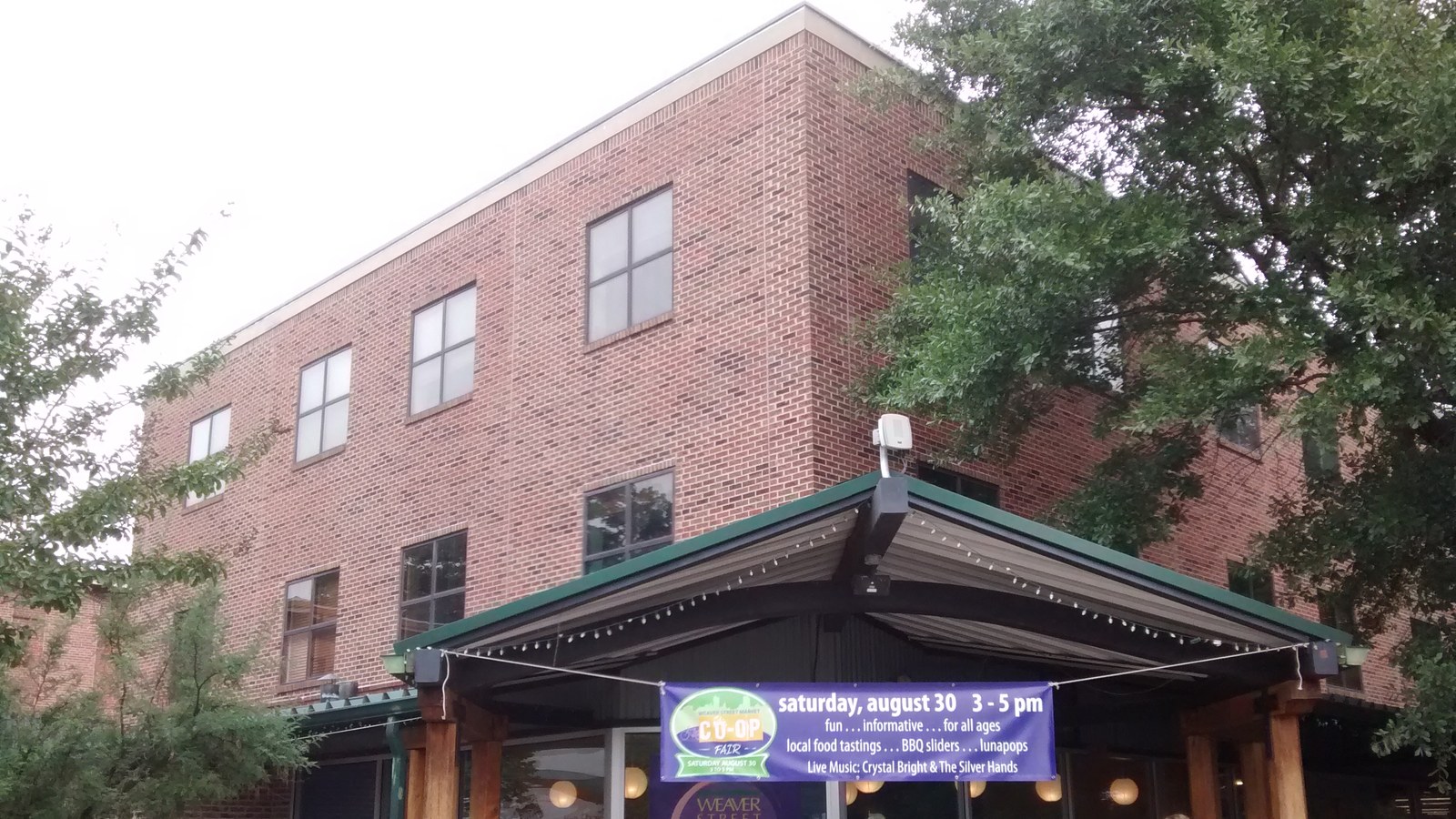 The brick Weaver Street Market building in downtown Carrboro, with a community event banner over the entrance