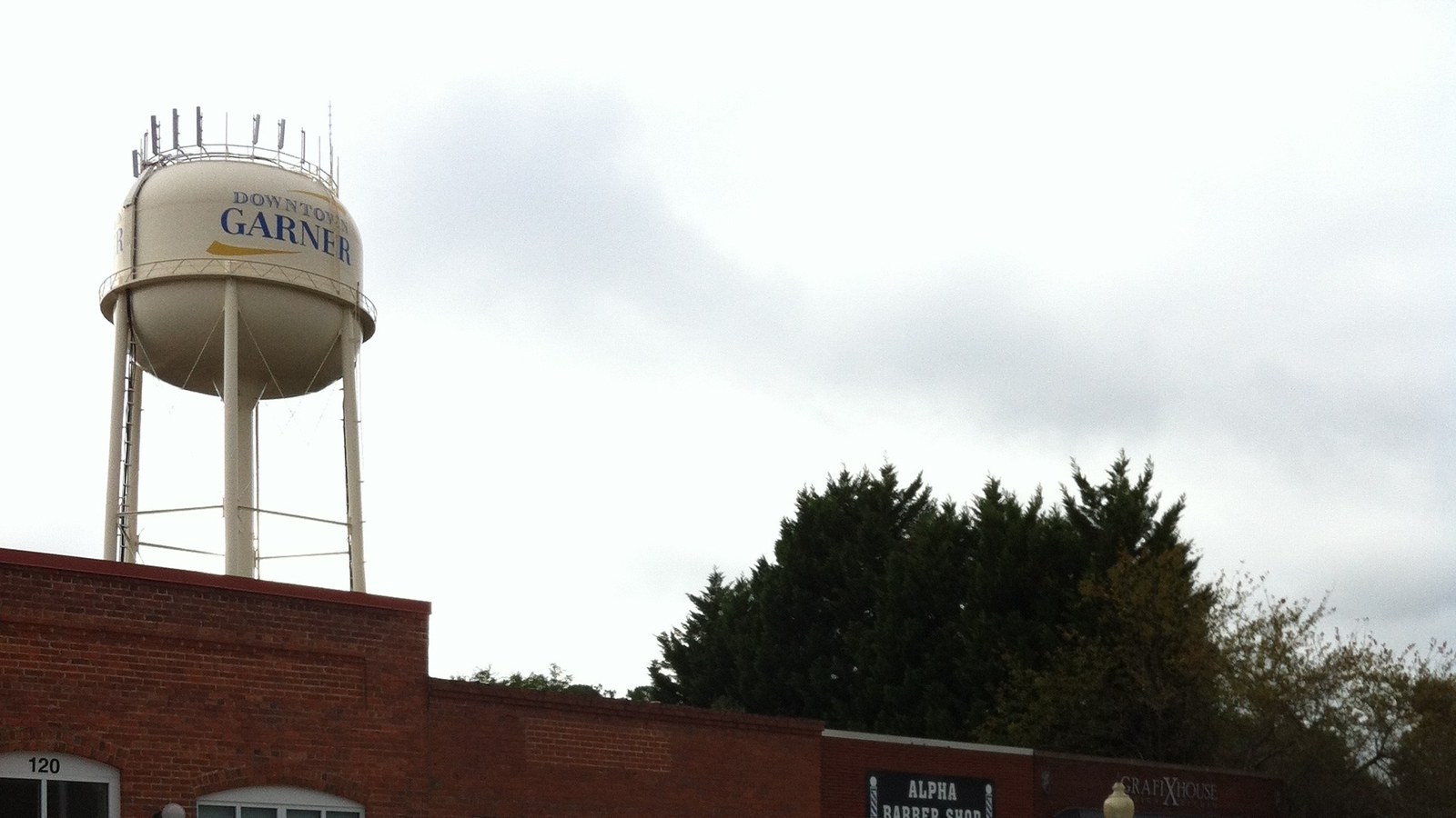 The Downtown Garner water tower rising above a brick storefront building