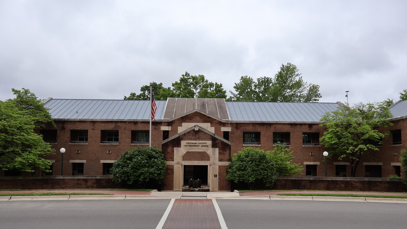 The Chatham County Government Annex in Pittsboro, a symmetric brick building with a standing-seam metal roof and an American flag out front