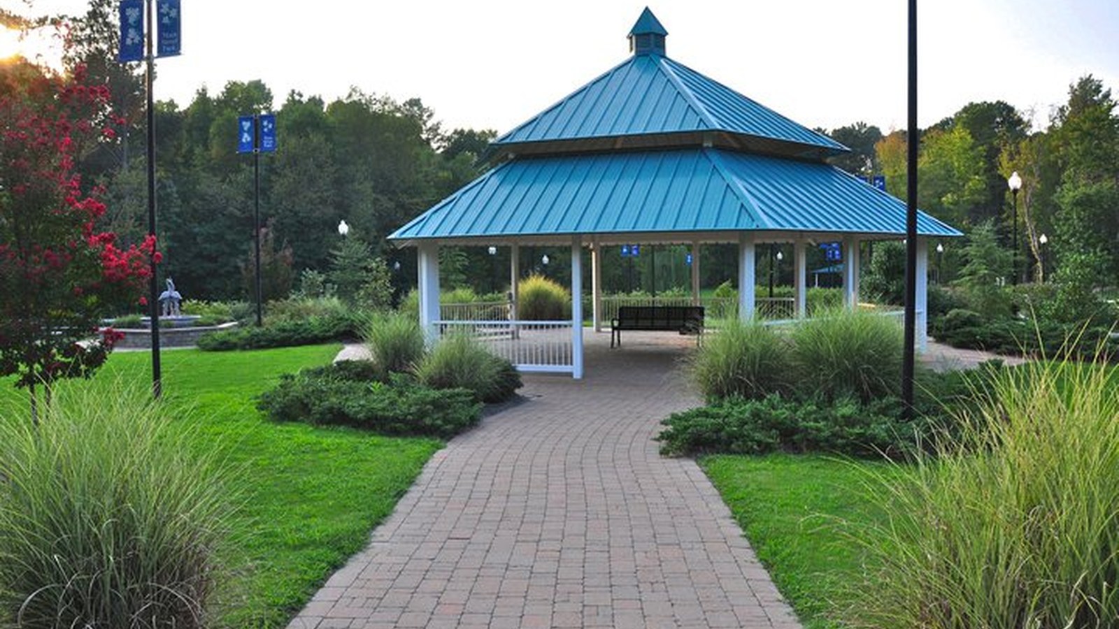 A blue-roofed gazebo along a brick walkway in Rolesville's Main Street Park, surrounded by landscaped grasses