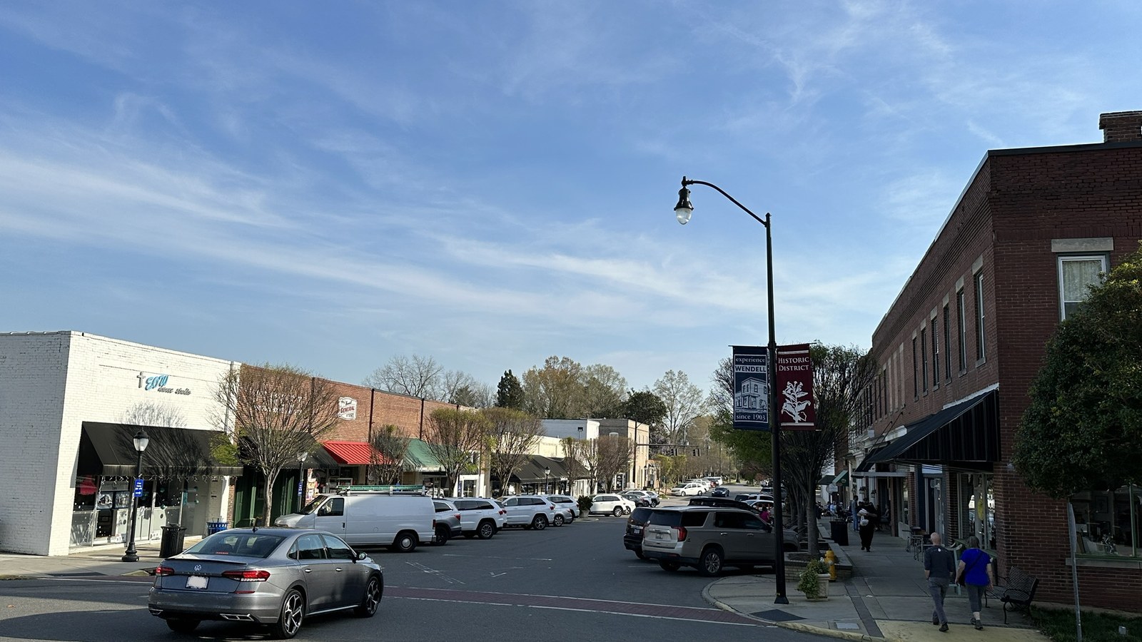 Downtown Wendell street scene with brick storefronts, angled parking, and a banner marking the Historic District