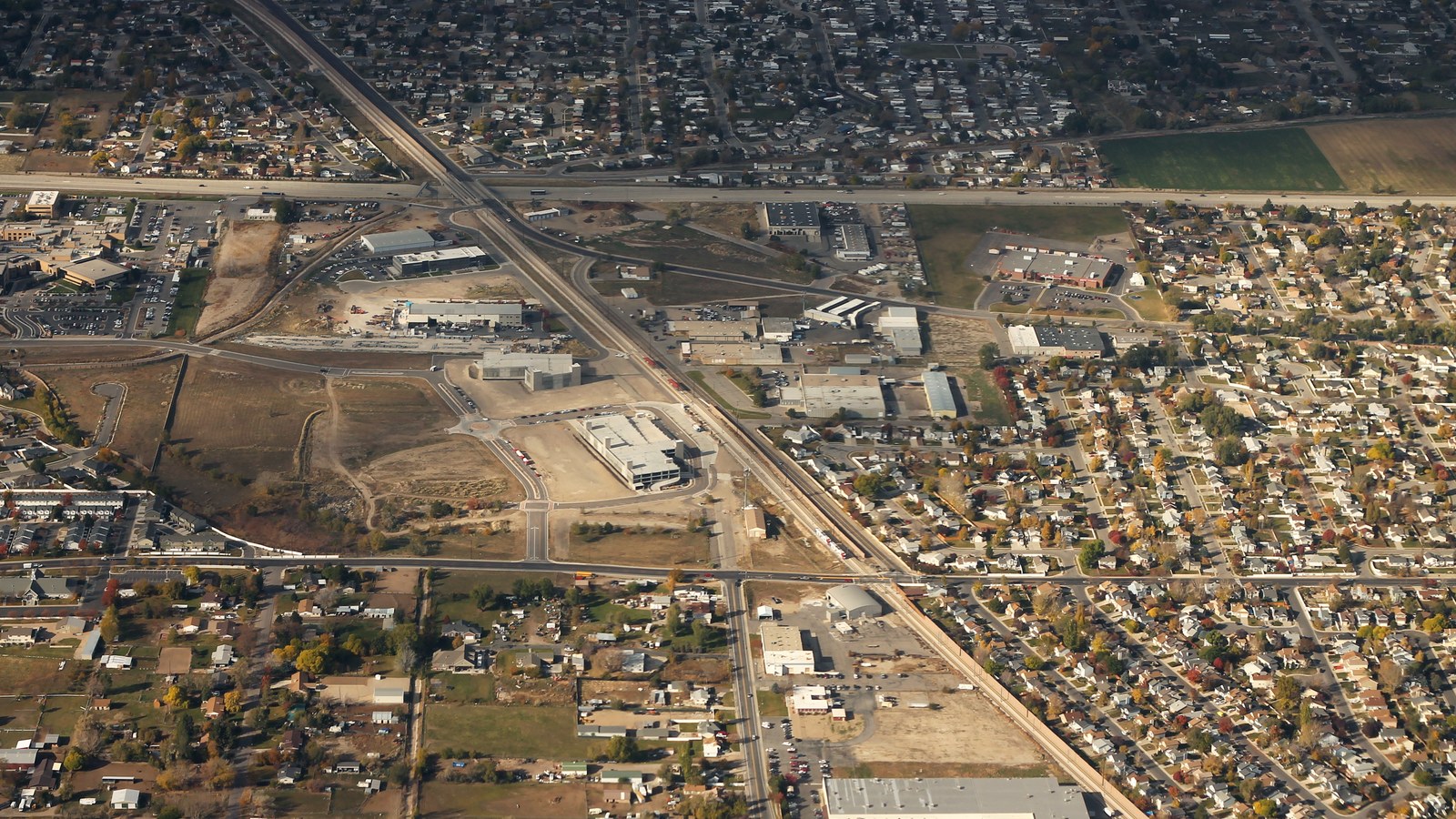 Aerial view of West Jordan, Utah, with TRAX light-rail tracks running through a mix of residential subdivisions and commercial buildings